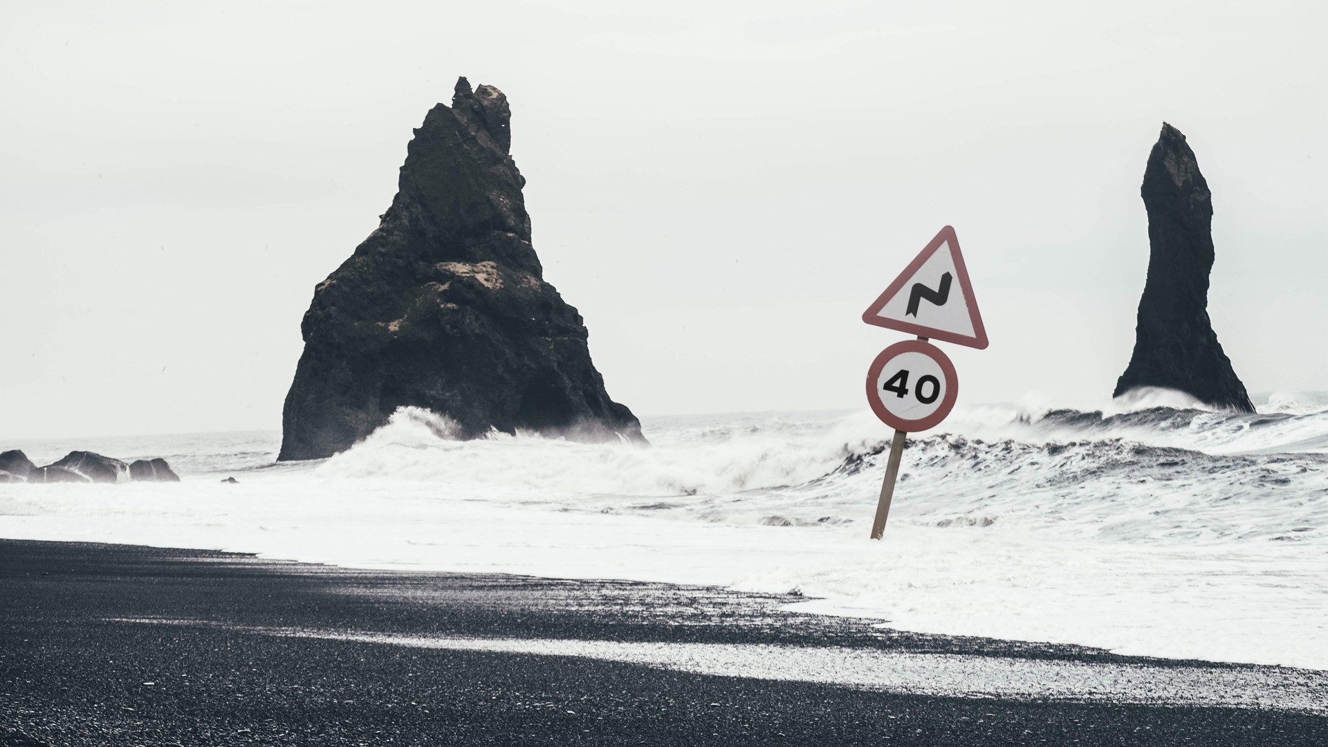 Beach Sign Waves Road Sign Mist Rock Humor Sea Gray Black Sand Water Splashes Rock Formation Horizon 1920x1080